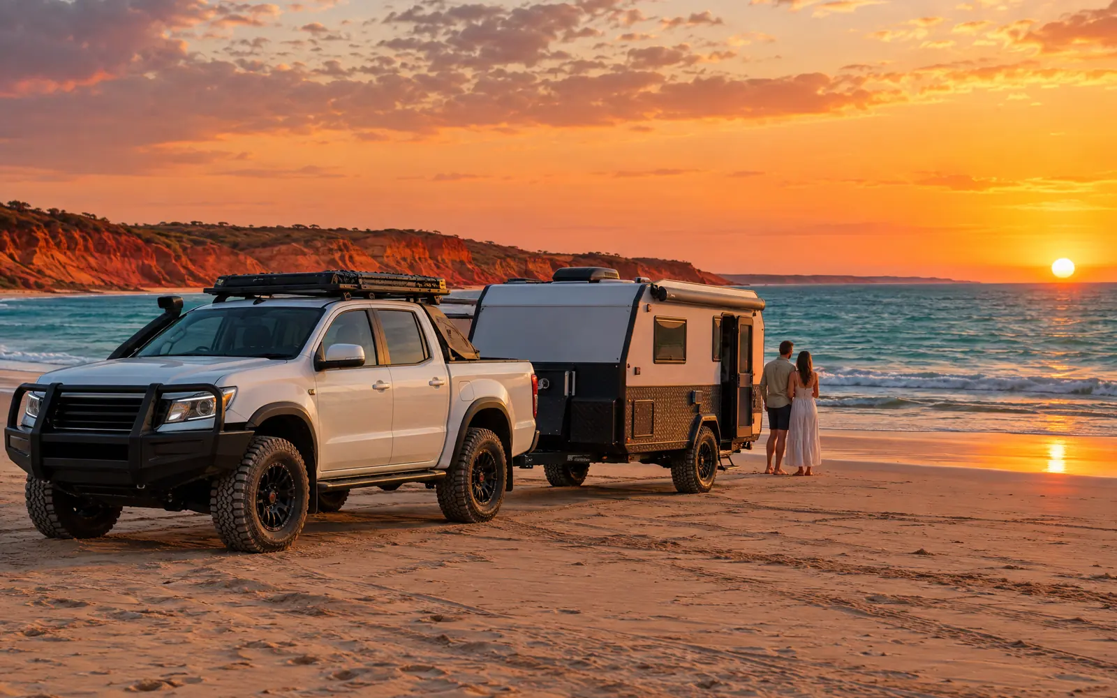 White dual-cab 4WD towing an off-road caravan on Cable Beach, Broome, at sunset